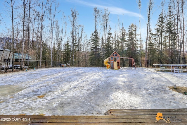 yard layered in snow with playground community, a trampoline, and fence