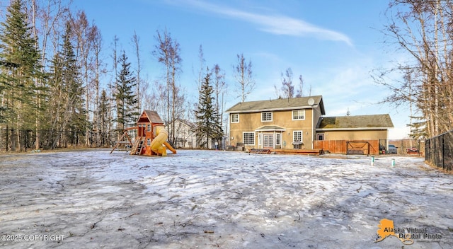 back of property featuring a wooden deck, fence, and a playground