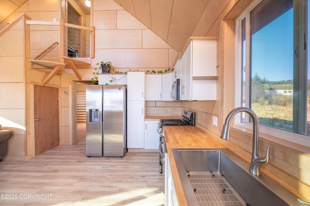 kitchen featuring a sink, stainless steel appliances, butcher block countertops, and white cabinetry