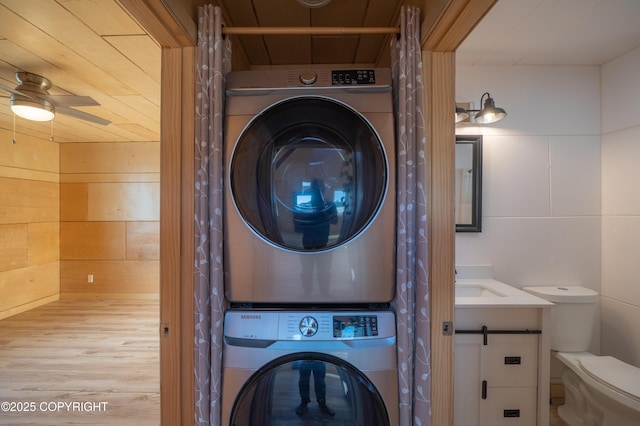 laundry area featuring stacked washer / dryer, tile walls, and a sink