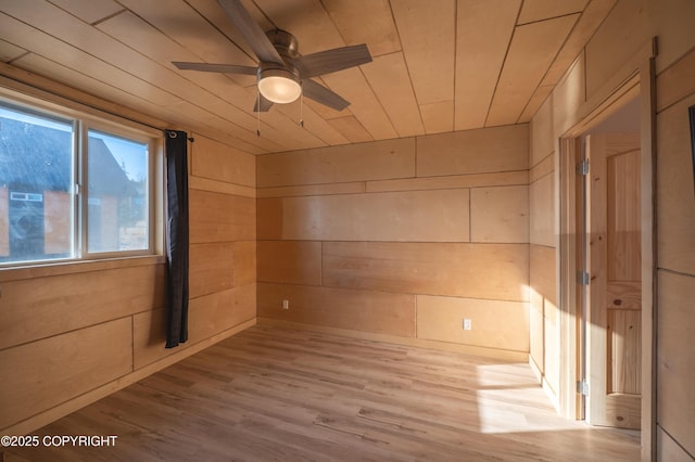 unfurnished room featuring wood walls, wooden ceiling, a ceiling fan, and wood finished floors