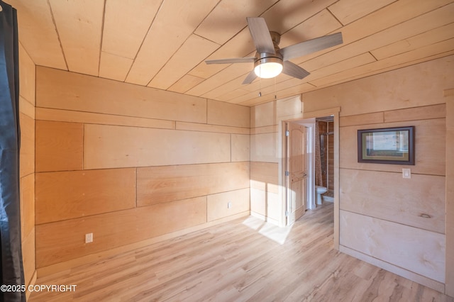 unfurnished room featuring wood ceiling, wood walls, a ceiling fan, and light wood finished floors