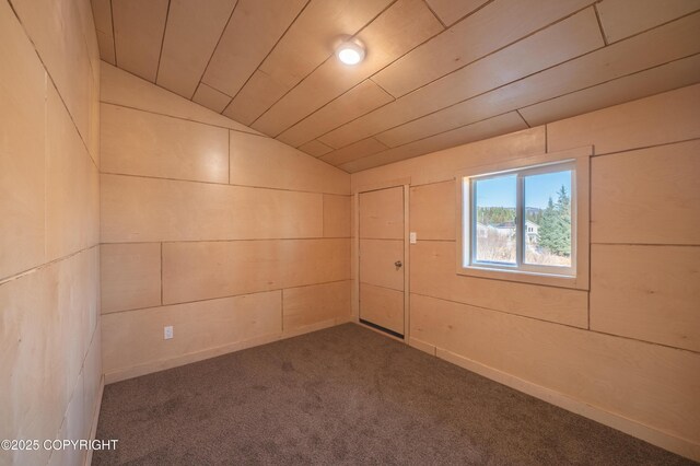 carpeted empty room featuring wood walls, wood ceiling, and lofted ceiling