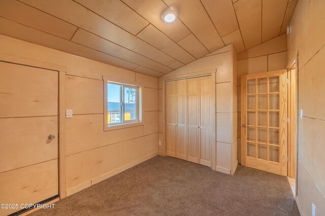 unfurnished bedroom with a closet, wood ceiling, lofted ceiling, and carpet floors