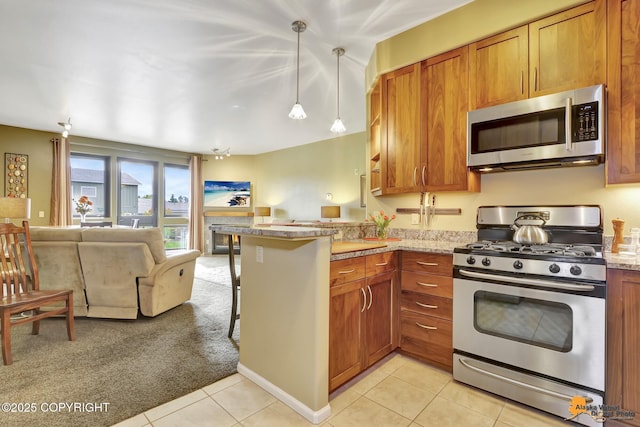 kitchen featuring brown cabinets, a kitchen breakfast bar, open floor plan, stainless steel appliances, and a peninsula