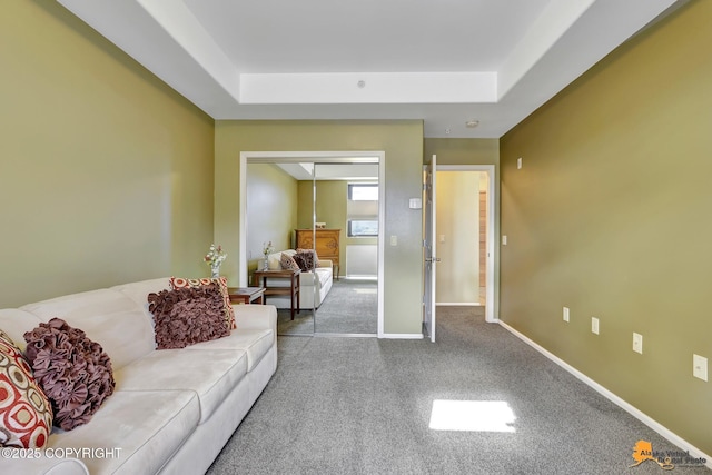 carpeted living room with a tray ceiling and baseboards