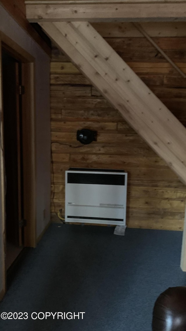 additional living space featuring heating unit and wood walls