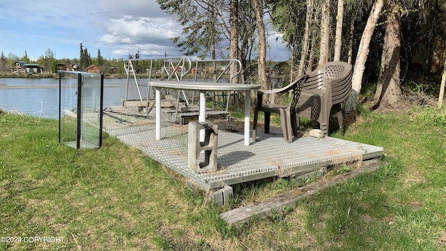 wooden terrace featuring a water view and a lawn