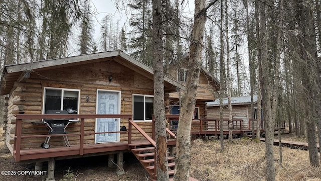 rear view of house featuring log siding, metal roof, and a deck