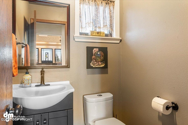 bathroom featuring vanity, toilet, and a textured wall