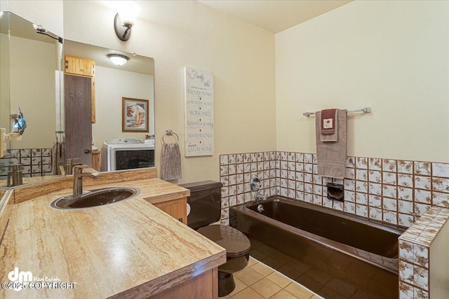 full bathroom with toilet, washer / clothes dryer, tile patterned flooring, a bath, and vanity