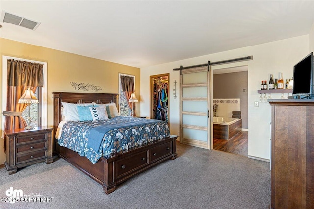 carpeted bedroom featuring visible vents, ensuite bath, a barn door, a closet, and a spacious closet