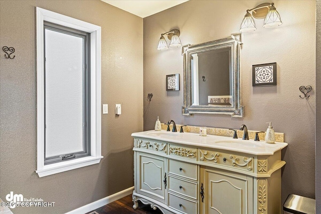 full bathroom with double vanity, wood finished floors, baseboards, and a sink