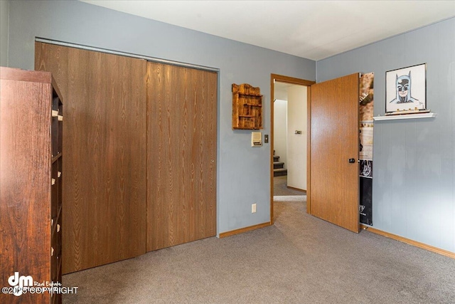 unfurnished bedroom with a closet, carpet floors, and baseboards