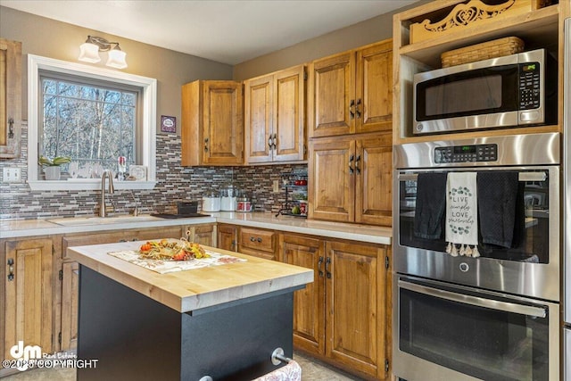 kitchen with a sink, decorative backsplash, butcher block countertops, and stainless steel appliances