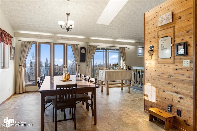 dining space featuring a skylight, a notable chandelier, baseboards, and a textured ceiling