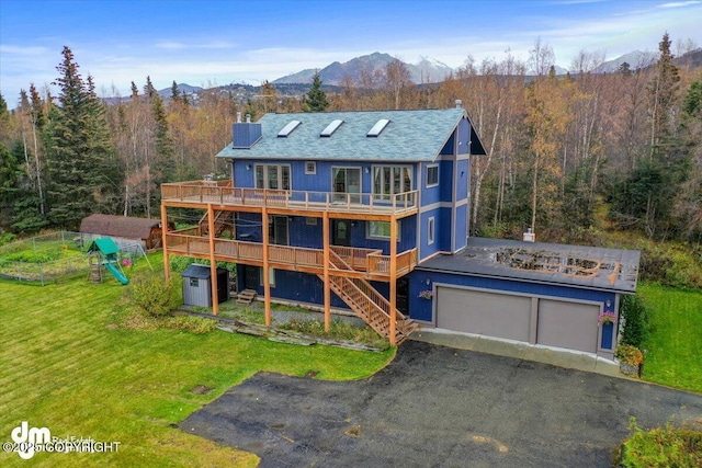 back of property featuring stairs, a lawn, a storage shed, an outdoor structure, and a deck with mountain view