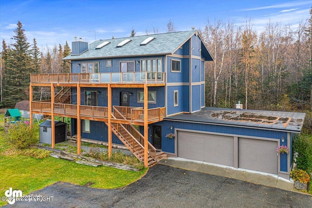 back of house with an outbuilding, a chimney, stairs, a storage unit, and a deck