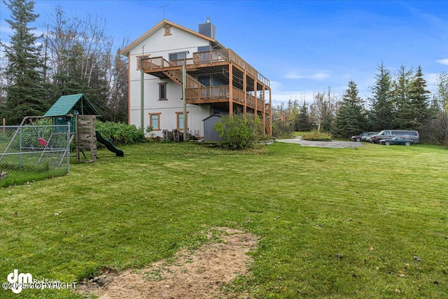 rear view of house with fence, a lawn, a chimney, and a playground