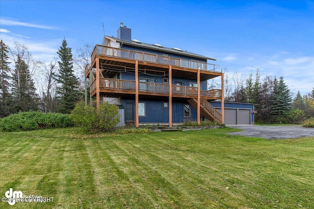 back of property with stairs, a chimney, a yard, a garage, and an outdoor structure