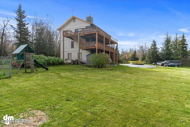 rear view of property with a chimney, a playground, and a yard