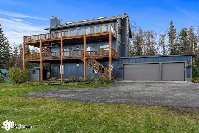 rear view of house featuring a storage unit, an outbuilding, a lawn, aphalt driveway, and stairs