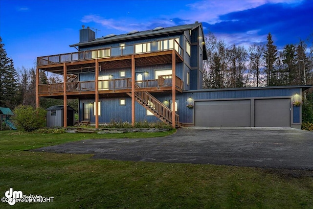 rear view of house featuring a shed, stairway, a lawn, an outdoor structure, and driveway