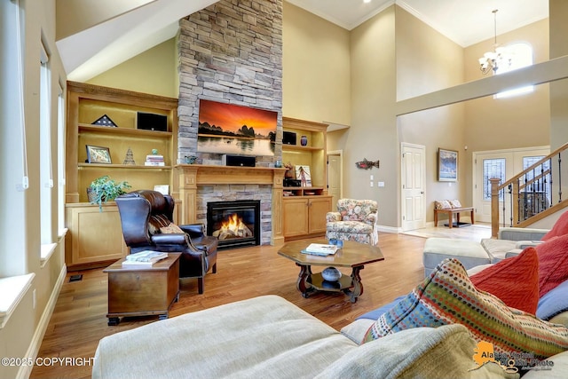 living area featuring ornamental molding, a chandelier, a fireplace, and light wood finished floors