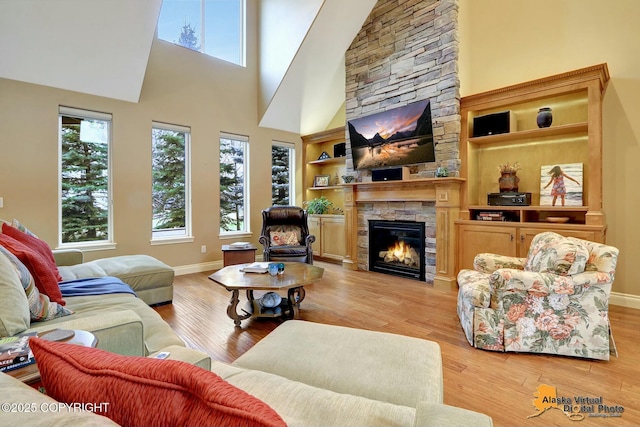 living area featuring light wood finished floors, a fireplace, and baseboards