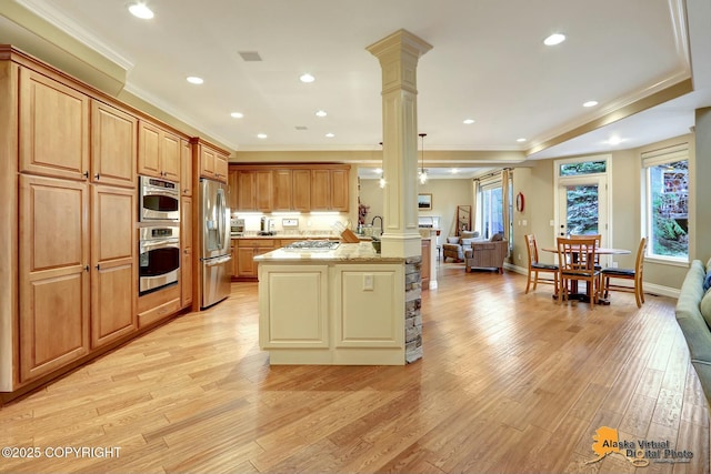 kitchen with a wealth of natural light, open floor plan, stainless steel appliances, a peninsula, and decorative columns