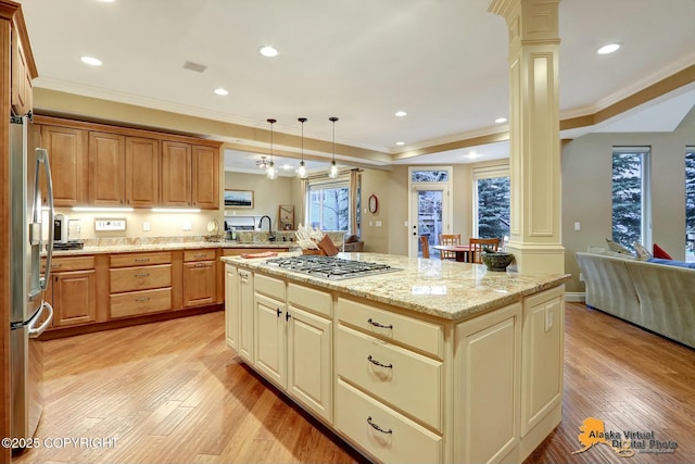 kitchen with light wood-style flooring, stainless steel appliances, crown molding, and ornate columns