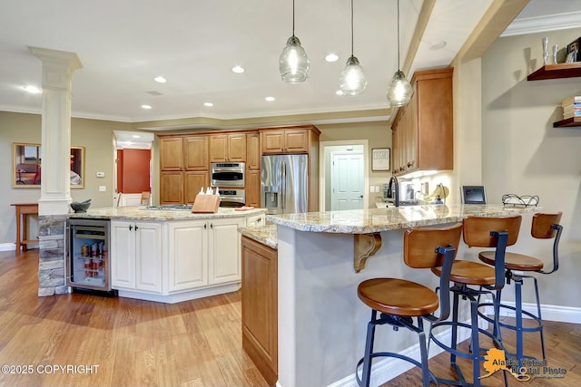 kitchen with light wood finished floors, ornate columns, a peninsula, stainless steel appliances, and wine cooler