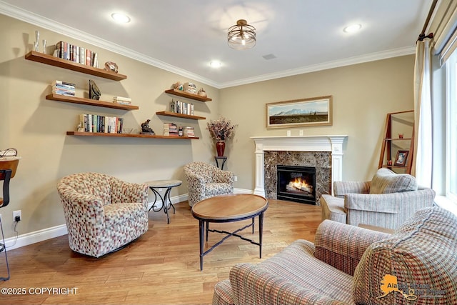 sitting room featuring baseboards, light wood-style floors, ornamental molding, and a fireplace