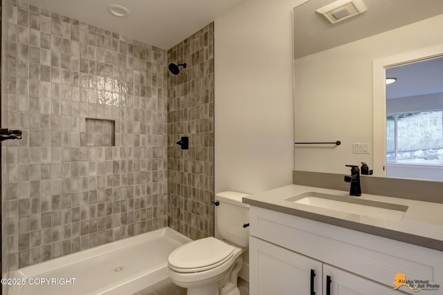 bathroom featuring a tile shower, toilet, and vanity