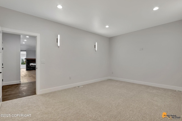 unfurnished room with a fireplace, recessed lighting, baseboards, and carpet floors