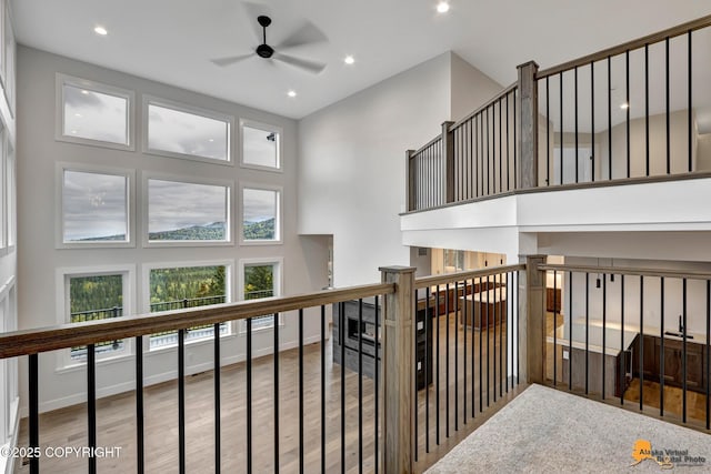 corridor with a towering ceiling, wood finished floors, baseboards, and a wealth of natural light