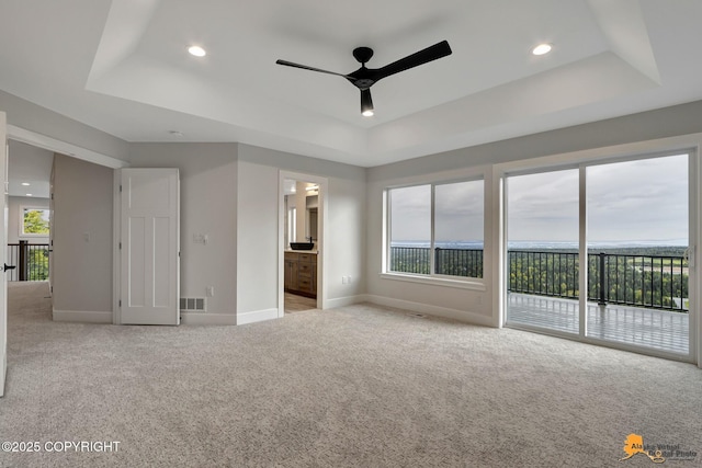 unfurnished bedroom featuring light colored carpet, a raised ceiling, access to exterior, and visible vents