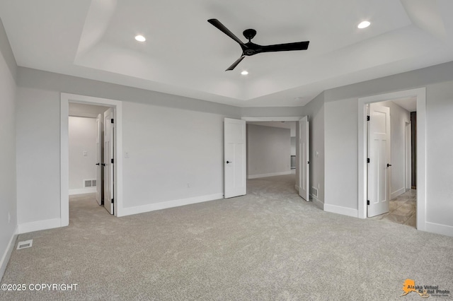 unfurnished bedroom featuring a raised ceiling, recessed lighting, and light colored carpet