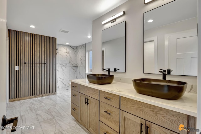 bathroom with double vanity, marble finish floor, a walk in shower, and a sink