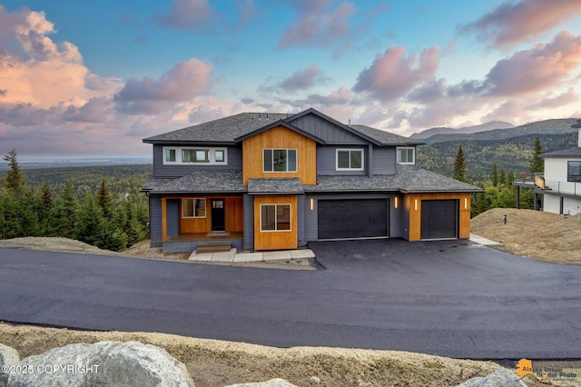 view of front of property with driveway, a mountain view, board and batten siding, a shingled roof, and a garage