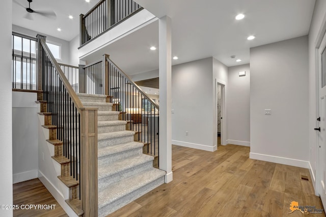 stairway featuring recessed lighting, wood finished floors, and baseboards