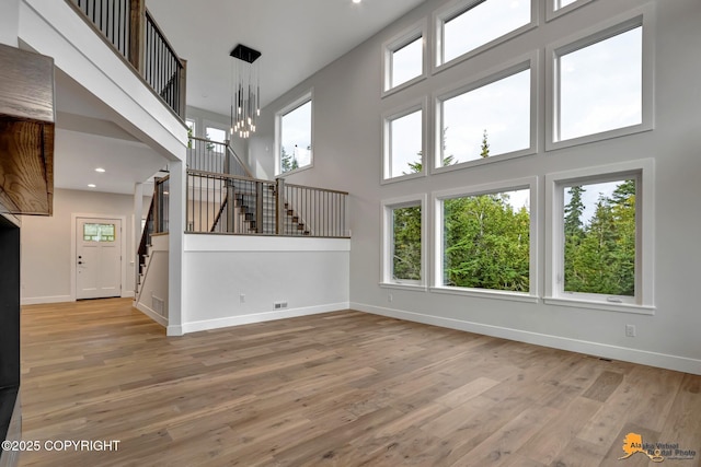 unfurnished living room featuring baseboards, a healthy amount of sunlight, wood finished floors, and stairs