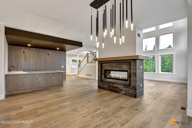 unfurnished living room featuring a wealth of natural light, visible vents, a multi sided fireplace, and wood finished floors