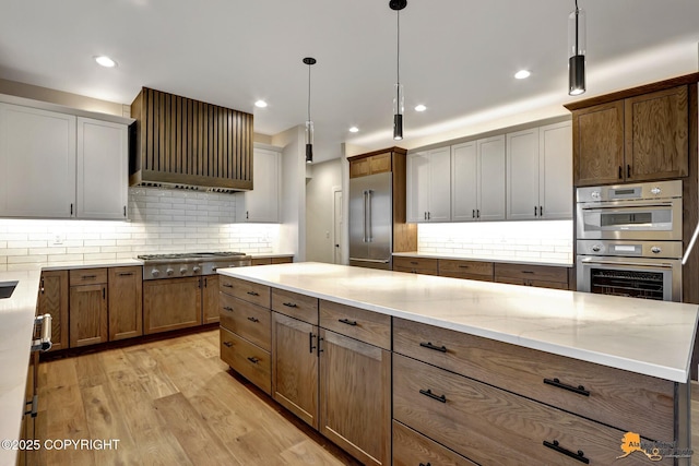 kitchen featuring wall chimney exhaust hood, light wood-style floors, backsplash, and stainless steel appliances