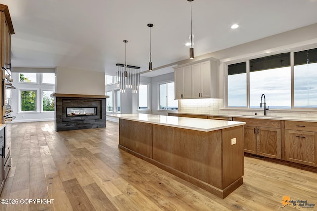 kitchen featuring light wood finished floors, decorative backsplash, light countertops, and a sink