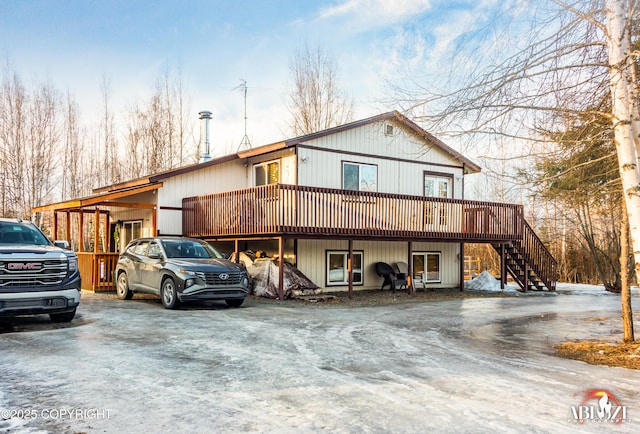 view of front of home with driveway, a wooden deck, and stairs