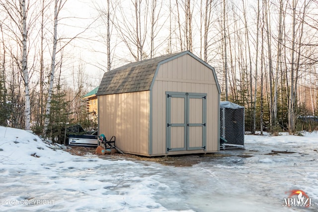 snow covered structure with an outdoor structure and a shed