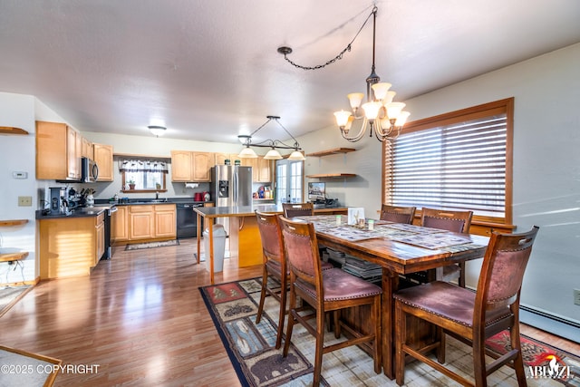 dining room featuring a healthy amount of sunlight, an inviting chandelier, and wood finished floors