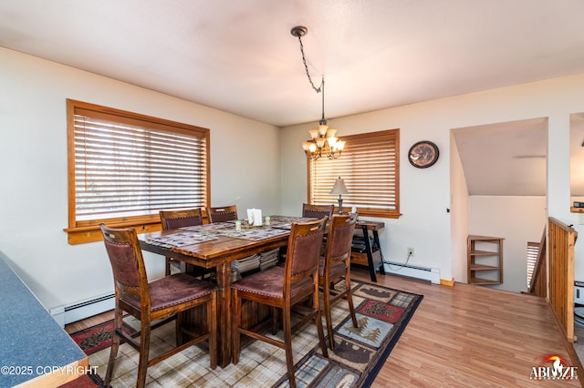 dining space featuring a chandelier, baseboard heating, and light wood-style floors