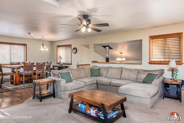 living area with ceiling fan with notable chandelier